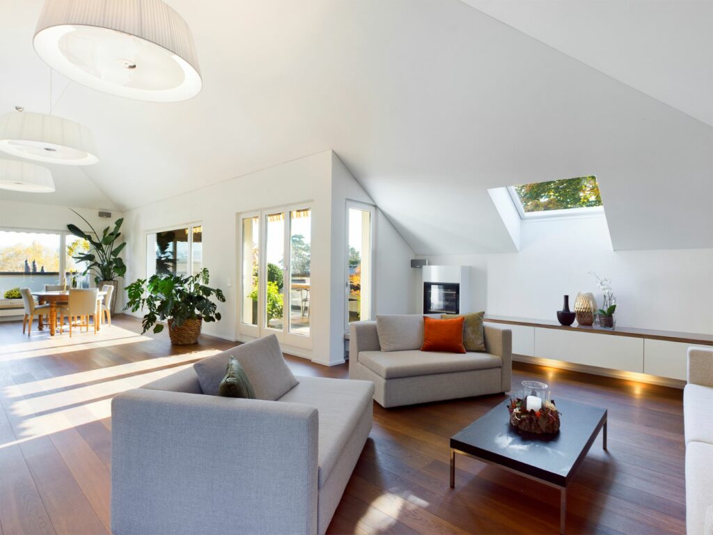 Schön dekoriertes Wohnzimmer mit Dachschräge und hellen Wänden. Bilder wie dieses helfen beim Immobilienverkauf.