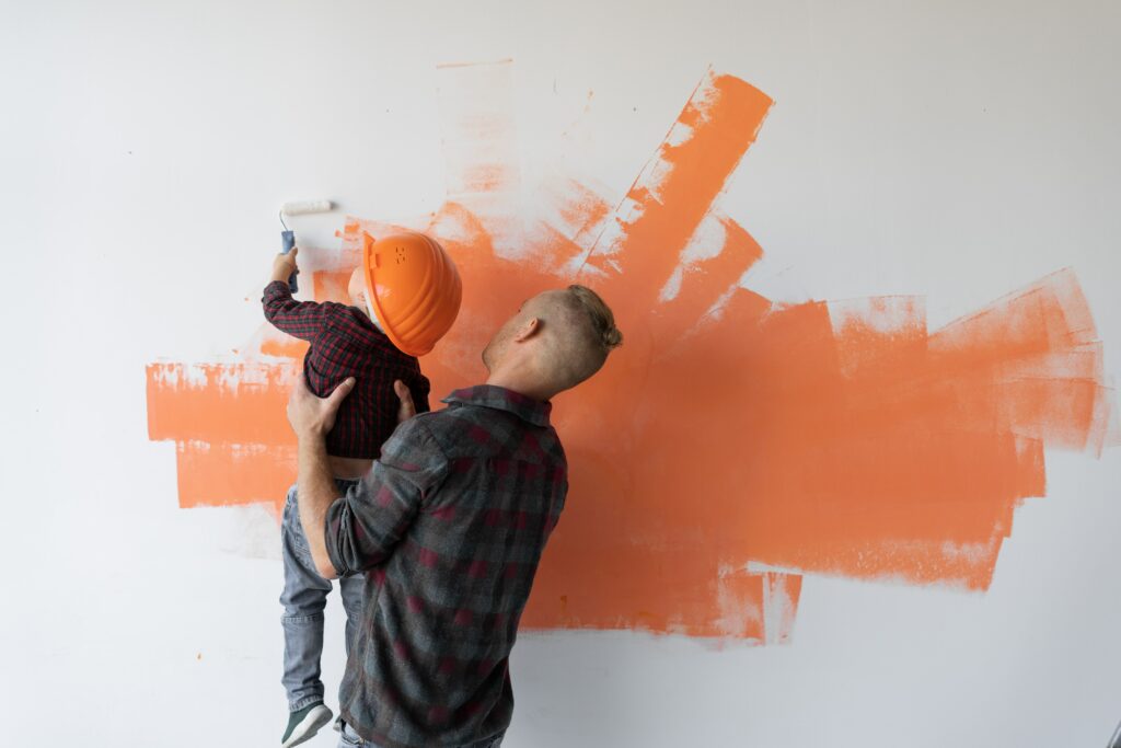 Vater und Sohne streichen gemeinsam die Wand beim wohnung renovieren..